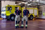 v.li.: Damien Cerni und Keith Miles stehen vor einem Feuerwehrauto in der Garage der Feuerwache. Der Flughafen Melbourne verfügt über einen eigenen Flugrettungsdienst.