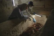 Zwei Arch&auml;ologen, Maysa Rabeeh (L) und Mohammed Refaat (R), untersuchen den zerfallenen Holzsarg von Ayawet mit einem Lichtstab. Sie untersuchen die &Uuml;berreste auf Hinweise auf eine zweite Bestattung.