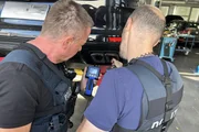 Mit einer Sonde suchen Polizeihauptkommissare Klaus Preis (l.) und Daniel Wenzke nach illegalen Veränderungen am Auspuff eines Sportwagens.