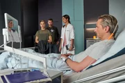 Alex (Jan Hartmann) und Laura (Susan Hoecke, r.) bringen Susanne Reichert (Maike Jüttendonk) ins Krankenzimmer ihres Vaters Matthias (David C. Bunners). Die Anspannung von Tochter und Vater ist deutlich zu spüren.