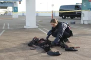 Brennan (Emily Deschanel) untersucht auf einem Parkdeck die Leiche eines Mannes, dessen Hand mit dem befestigten Koffer abgeschnitten wurde.