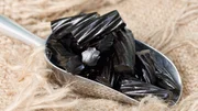 A scoop of old fashioned black liquorice candy on frayed burlap.