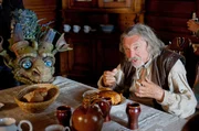 Der Drache Drako hilft dem Gro&szlig;vater (Karel Gott) in der Schmiede - und beim Essen.