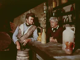 Der schie&szlig;freudige Desperado Joe (Clint Eastwood, l.) kommt in die abgelegene Stadt San Miguel. Dort erf&auml;hrt er von einem Salonbesitzer (Pepe Calvo, r.), dass der Ort von zwei verfeindeten Banden terrorisiert wird ...