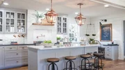 The Ward's new kitchen is completely transformed with new cabinetry, appliances, and wood flooring. Copper light fixtures and a large island are installed, as seen on Fixer Upper. (After)
