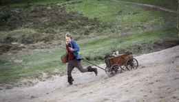 Hans (Anton Spieker) ist mit seinem getauschten Schwein im Bollerwagen im Gl&uuml;ck.