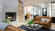 As seen on Fixer Upper, the living room in the Wixsom's remodeled house has new hardwood floors, concrete walls and a fireplace that separates the kitchen from the living room.