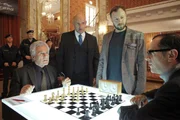 Der Veranstalter des Schachturniers Arthur Lippmann (Michael Rast, 2.v.l) und sein Sicherheitschef Laska (Ivan Shvedoff, 2.v.r) müssen den beiden um den Weltmeistertitel kämpfenden Favoriten Sorokin (Gojko Mitic, l) und Boris Aljechin (Merab Ninidze) mitteilen, dass das Schachturnier aufgrund einer Bombendrohung abgebrochen werden muss.