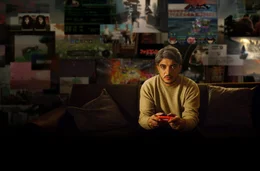 Was kostet der Erfolg von Videospielen?: Host Khesrau Behroz sitzt mit Videospiel-Controller auf dem Sofa.