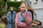 Nina (Julia E. Lenska, l.) und Lars (Ingo Naujoks, r.) hören Tanja (Frankziska Arndt, r.) bei einem Telefongespräch zu. Tanja wirkt erschöpft.