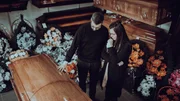 Undertaker showing coffins and crosses to a widow