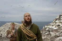 Reenactors Wikinger in einer T&ouml;lpel-Kolonie mit hunderten von T&ouml;lpel, die &uuml;ber Bass Rock in Schottland fliegen.