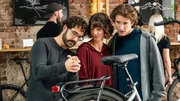Das Influencer-P&auml;rchen Hanna (Sophie Schl&uuml;ter, M.) und Tom (Benedikt Kalcher, r.) reist mit seinem Van durch Europa und begeistert tausende Fans. Nach einem "Meet and Greet"-Event im Fahrradladen von Farsad Reza (Giovanni Funiati, l.) wird Hanna pl&ouml;tzlich tot vor ihrem Van aufgefunden. (Komparsen im Bild)