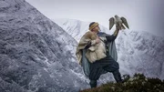 Ein Reanactor-Wikinger und ein Gerfalke (Gyrfalcon) in der verschneiten Landschaft des Alladale Naturschutzgebiet in Schottland.