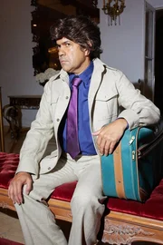 Ein Mann sitzt und hält einen Koffer in der Hand