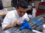 Sesame Street Cake. Buddy adds fine details to the modeling chocolate fur of Cookie Monster.