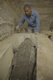 Der Deckel des Sarkophags des Priesters Tjanimit wurde entfernt, so dass Ramadan die wunderschöne Mumie darin betrachten kann. Die Mumie ist mit einem Perlennetz geschmückt und muss mit großer Sorgfalt behandelt werden.