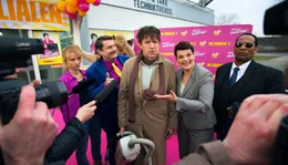 Statt jemanden zu finden, der ihm den museumsreifen Fuzzbuster-Stausauger repariert, ger&auml;t Hubert Lotzmann (J&ouml;rg Gudzuhn, Mitte) in die Er&ouml;ffnung des 999. Elektromarktes von Konzernchefin Brenda (Gayle Tufts, re.) mit Marktleiter Schleicher (Peter Trabner, 2. v. li.), Mitarbeiterin Gabi (Christina Gro&szlig;e, li.) und Brendas Bodyguard (Eric Lee Johnson, re.).