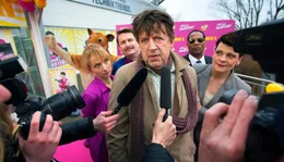 Hubert Lotzmann (J&ouml;rg Gudzuhn) im Fokus: Konzernchefin Brenda (Gayle Tufts, re.), Marktleiter Schleicher (Peter Trabner, hinten links), Mitarbeiterin Gabi (Christina Gro&szlig;e, li.) und Brendas Bodyguard (Eric Lee Johnson, hinten rechts) st&uuml;rzen sich auf den vermeintlichen Kunden.