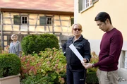 Friderike v. Lubitz (Merle Wasmuth, l.) beobachtet Nele Fehrenbach (Floriane Daniel, M.) und ihren zukünftigen Schwager Johannes v. Endingen (Yung Ngo, r.) bei der Übergabe eines Durchsuchungsbefehls für das Weingut. Der Chef der Weinproduktion hatte den toten Erntehelfer entlassen, weil er ihn beim Weinklauen erwischt hatte. Friderike v. Lubitz (Merle Wasmuth, l.) beobachtet Nele Fehrenbach (Floriane Daniel, M.) und ihren zukünftigen Schwager Johannes v. Endingen (Yung Ngo, r.) bei der Übergabe eines Durchsuchungsbefehls für das Weingut. Der Chef der Weinproduktion hatte den toten Erntehelfer entlassen, weil er ihn beim Weinklauen erwischt hatte.