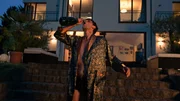 Eiko Nehring (Franz Liebig) steht im Morgenmantel und mit Champagnerflasche am Mund im Garten einer imposanten Villa. Er ist sichtlich betrunken und torkelt.