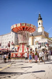 Besucher*innen der Rupertikirtag fahren mit dem Kettenkarussell