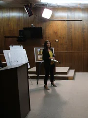 Fatima Silva giving presentation to jury in front of evidence boards before the mock trial in a courtroom. Fatima Silva giving presentation to jury in front of evidence boards before the mock trial in a courtroom.