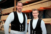 Zimmermannsmeister Burkhard (l, 44 J.) und Dachdecker-Azubi Nick (19) vor dem Holzlager.