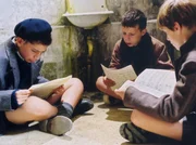 Der Lausejunge Pierre Morhange (Jean-Baptiste Maunier, rechts) hat mit seinen Mitsch&uuml;lern Corbin (Thomas Blumenthal, links) und Le Querrec (Cyril Bernicot) die Noten seines Lehrers Mathieu gestohlen. Auf der Toilette betrachten die drei Jungs etwas ratlos ihre r&auml;tselhafte Beute.