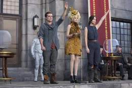 Auch Effie (Elizabeth Banks, M.) kann ihre "Z&ouml;glinge" Katniss (Jennifer Lawrence, r.) und Peeta (Josh Hutcherson, l.) nicht davon abhalten, deutliche Zeichen zu setzen. Deshalb beschlie&szlig;t Pr&auml;sident Snow, die beiden dauerhaft und endg&uuml;ltig aus dem Verkehr zu ziehen ...