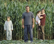 Fassungslos stehen (v.l.n.r.) Morgan (Rory Culkin), Graham (Mel Gibson), Bo (Abigail Breslin) und Merrill (Joaquin Phoenix) vor den r&auml;tselhaften Kornkreisen, die er auf seinem Feld entdeckt. Noch w&auml;hrend er die &Uuml;belt&auml;ter in seiner n&auml;heren Umgebung sucht, tauchen weltweit &auml;hnliche Ph&auml;nomene auf ...