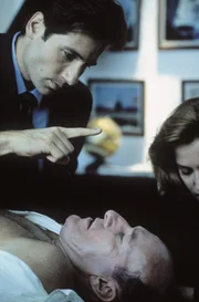 Projektleiter Colonel Belt (Ed Lauter, vorne) wird von einer fremden Macht gesteuert. Mulder (David Duchovny, l.) und Scully (Gillian Anderson, r.) versuchen, ihn zu retten.