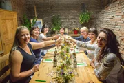 Frauen prosten sich an der Dinnertafel zu, von links vorne: Heidi Kaiser, Birgit Vogl, Theresa Frantz und am Kopfende Katharina Mayer. Von rechts vorne: Cathy Lichtmannegger, Edeltraud Zehetmeier und Barbara Baumann.