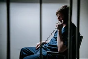 Mann hinter Gittern am Telefon.