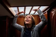 Tessa (Sabine Urban) versucht panisch aus einer Kajüte zu entkommen. Dabei schlägt sie mit den Händen über dem Kopf gegen die Kajütendecke.