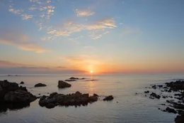Die Sonne f&auml;rbt den Himmel &uuml;ber einer der vielen einsamen Buchten von Menorca.