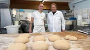 Bäckermeister Torsten Woeste (l.) lässt Björn Freitag bei der handwerklichen Herstellung von Aufbackbrötchen mit anpacken.