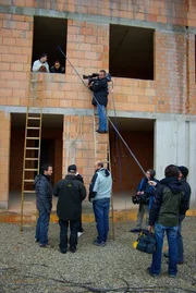 GRIPS Mathe - Übungen hautnah: Dreharbeiten zum Lösen einer Pythagoras-Aufgabe. Lehrer Basti Wohlrab (links unten) hat mit den Schülern gewettet, wer am genauesten die Höhe bis zum Fenster berechnet. Die Schüler messen nach - Basti gewinnt, er hat über die Leiterlänge den Pythagoras angewendet.
