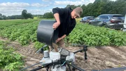 Drohnenpilot Carsten Hinrichs f&uuml;llt die Drohne mit Saatgut. Mit dem technischen Ger&auml;t soll ein Pflanzengemsich &uuml;ber bereits wachsenden Kartoffeln ausgebracht werden. Als eine wasser- und kohlenstoffspeichernde "Unterfrucht".