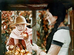 Die verkleidete b&ouml;se Stiefmutter (Marianne Christine Schilling) bietet Schneewittchen (Doris Weikow) einen vergifteten Apfel an.