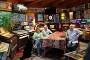 Jukebox-Sammler Kurt Kager (m.) mit Karin Kager und Plattensammler Harald Kogler umringt von Jukeboxen während Servus TVs "HL Stainz", Steiermark.