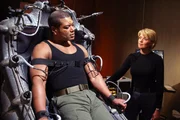 Teal'c (Christopher Judge, li.) soll den Simulator testen. Carter (Amanda Tapping) erklärt ihm genau wie er das Gerät abschalten kann...