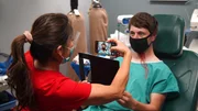 Dr. Sandra Lee takes a photo of Trey L. on exam chair with cell phone. Dr. Sandra Lee takes a photo of Trey L. on exam chair with cell phone.