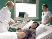 Dr. Isabel Dahl (Denise Zich, links) diagnostiziert einen Milzriss bei Aylin Demir (Suzan Demircan), der von einer seltenen Krankheit verursacht wird. Auch wenn Schwester Arzu Ritter (Arzu Bazman, rechts) skeptisch ist, veranlasst Isabel eine sofortige Operation.