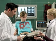 Als Dr. Philipp Brentano (Thomas Koch, links) die Schürfwunde von Rufus Fehn (Joseph K. Bundschuh) untersucht, entdeckt er, dass sich ein gefährlicher Gasbrand entwickelt hat. Brenatano macht Dr. Isabel Dahl (Denise Zich, rechts) Vorwürfe, Rufus nicht eingehend genug untersucht zu haben.