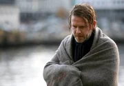 Nach einem Sprung ins Hafenbecken, der ihm das Leben rettete, ist Varg Veum (Trond Espen Seim) völlig durchnässt.