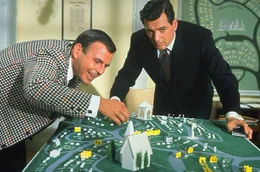 Mr. Akins (Paul Lynde, l.) zeigt dem Hypochonder George Kimball (Rock Hudson, r.) schon einmal seinen Platz auf dem Friedhof ...