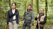 Die Forstbiologin Pia (Anna Puck) stapft mit Alex (Vinzenz Kiefer, M.) und Semir (Erdogan Atalay) durchs Unterholz zu ihrer Hütte im Wald.