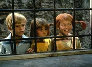 Erstaunt sehen Pippi (Inger Nilsson, r.), Tommy (Pär Sundberg, l.) und Annika (Maria Persson, M.) dem Treiben der Seeräuber in einer Taverne zu.