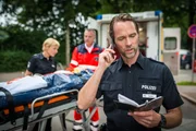 Melanie (Sanna Englund, l.) hat im Einsatz ein Mädchen (Amina Merai, M.) angefahren. Mattes (Matthias Schloo, r.) gibt den Kollegen vom Revier die Daten durch.